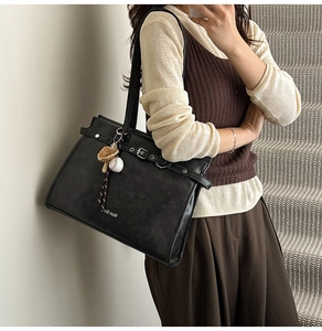 Detail of black matte leather tote bag with a unique baseball glove charm accessory
