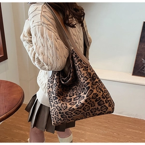 Detailed side view of leopard print tote bag with brown leather strap worn by a model