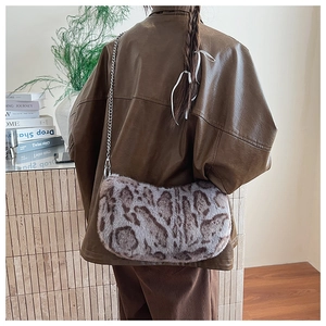Detail shot of a faux fur leopard print shoulder bag with a slim metal chain strap