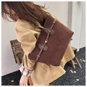 Detail of dark brown faux suede tote bag with leather strap and golden hardware