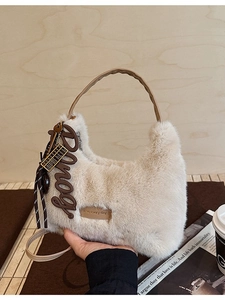 Schicke Handtasche aus cremefarbenem Kunstpelz mit Ledergriffen und Anhängern