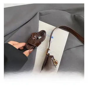 Detail view of the adjustable leather strap on a shiny brown shoulder bag with charm