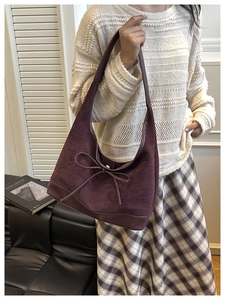 Detail of dark purple suede hobo bag with bow tie showing drape and texture on shoulder
