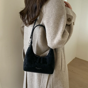 Detail of black suede hobo bag with Fashion & Bags Leather text on wool coat