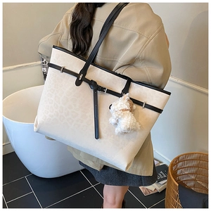 Lifestyle shot of large cream tote bag with black trim and cute plush puppy charm