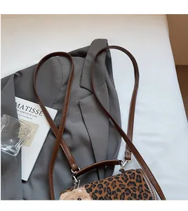 Leopard print crossbody bag with brown leather straps and a plush bear keychain
