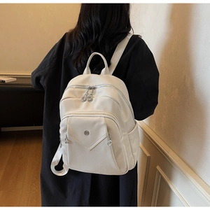Detail shot of a white lychee grain backpack with silver zippers and side pockets on a model