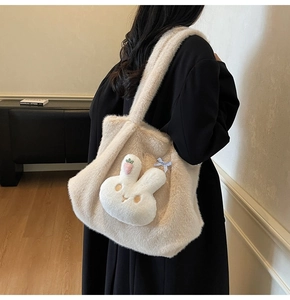 Detail of plush tote bag with cute rabbit head and blue bow on black coat
