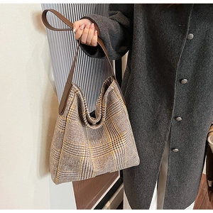 Detail view of plaid tote bag fabric texture with premium brown leather handles