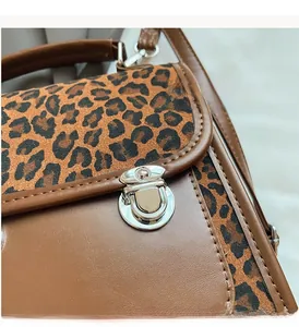Detail of silver twist lock and leopard print flap on brown leather handbag