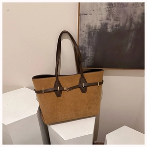 Detail of brown faux suede tote bag with leather straps and gold metal hardware