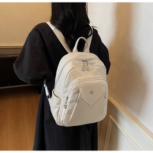 Detail view of cream lychee texture leather backpack with V-stitch pocket and silver zippers