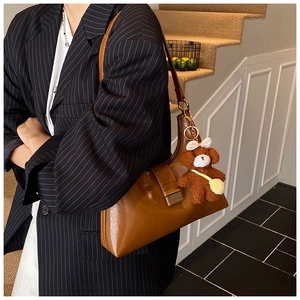 Brown faux leather shoulder bag with cute teddy bear charm and metallic buckle detail