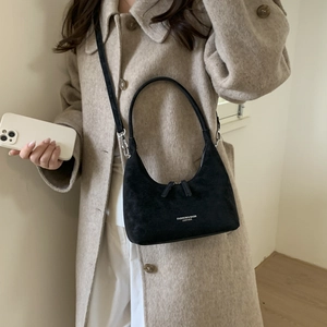 Detail of black suede leather crescent bag with adjustable strap and fashion logo text
