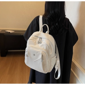 Rear view of a stylish white pebble grain leather backpack worn by a female model