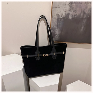 Close-up of black suede tote bag featuring a leather strap and gold metallic buckle detail