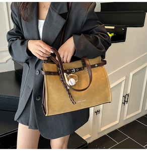 Close-up of khaki and brown拼接 tote bag with baseball charm detail and logo