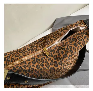 Close-up of leopard print fabric with golden metal zipper and black leather trim