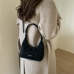 Close-up of black hobo dumpling bag with soft matte texture and gold brand logo