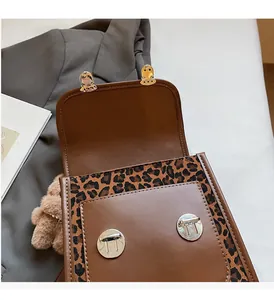 Detail of leopard print trim and silver metal clasps on a brown leather crossbody bag