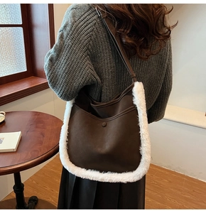 Detail of dark brown suede underarm bag with white faux fur trim on a female model