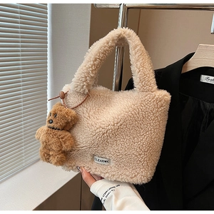 Detail of beige fuzzy lamb wool bucket bag featuring a cute teddy bear charm and logo tag