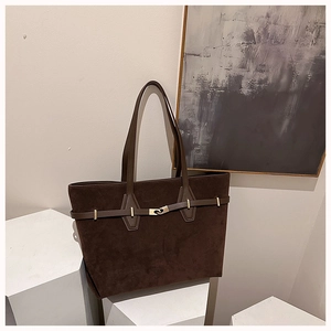 Detail of deep brown suede tote bag with leather buckle strap and long shoulder handles