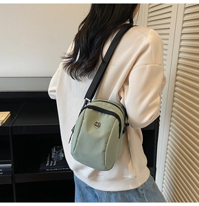 Detailed side view of light green nylon crossbody bag with adjustable black strap