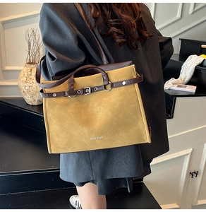 Retro mustard yellow suede tote bag with leather trim carried by a model on stairs