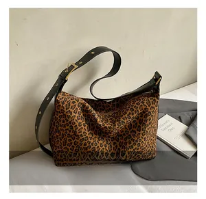 Close-up of leopard print shoulder bag featuring black leather strap and gold buckle