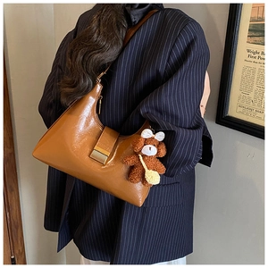 Detail of brown faux leather hobo bag featuring a metal buckle and cute bear charm accessory