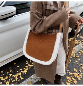 Detail of autumn brown suede underarm bag with white faux fur trim and round buckle