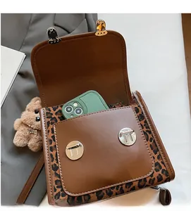 Detailed view of leopard print shoulder bag with functional front pocket and bear charm