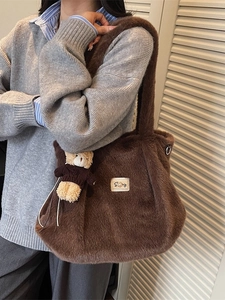 Bruine pluchen tote bag met parel-label en beertje bedeltje gedragen door een model