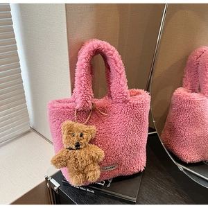 Detailed close-up of pink faux shearling bucket bag with cute brown plush bear charm