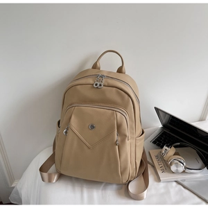 Detail view of khaki pebbled leather backpack with silver hardware in a workspace setting