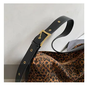 Detail of adjustable black leather strap with gold V-buckle on leopard print bag