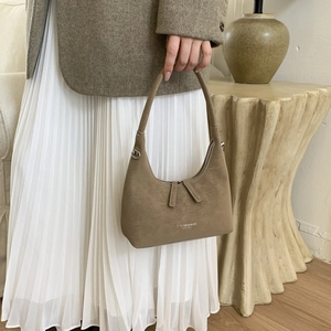 Close-up of brown suede dumplings bag with silver zipper and luxury leather texture
