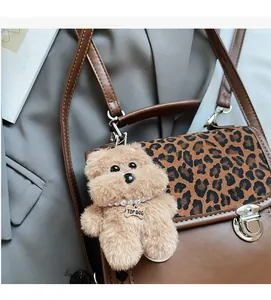 Detail of leopard print backpack with plush dog charm and elegant faux pearl collar
