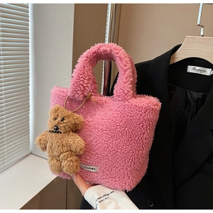 Pink plush bucket bag with brown teddy bear charm and brand tag detail shown in context