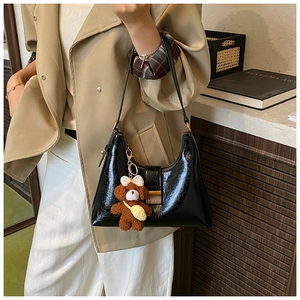 Polished black hobo bag with gold hardware and a cute brown teddy bear keychain detail