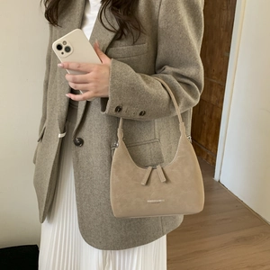 Detail showing high-quality beige suede dumpling bag texture and crossbody strap