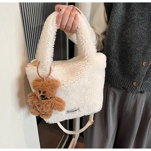 Detail of white plush bucket bag with brown bear charm and adjustable shoulder strap