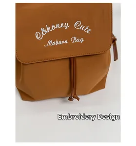 Detailed view of the intricate white embroidery on a brown nylon drawstring backpack