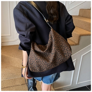 Chic leopard print tote bag with black leather strap worn by a model on stairs