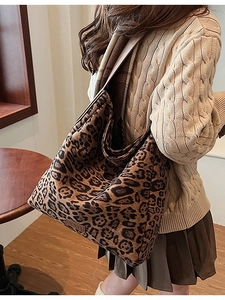 Large leopard print suede tote bag in hobo style worn by model in a cozy indoor setting