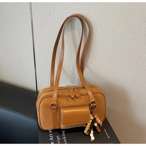 Detail of a brown suede shoulder bag with colorful wooden beads and side pocket accent