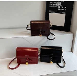Gros plan de trois sacs à bandoulière vintage en cuir marron, rouge et noir sur marbre