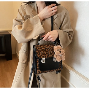 Détail du sac à main léopard avec rabat en cuir noir et breloque ours marron
