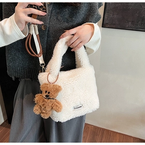 Detailed texture of white plush faux fur handbag with a cute brown bear charm